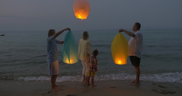 Família voando lanterna do céu na praia