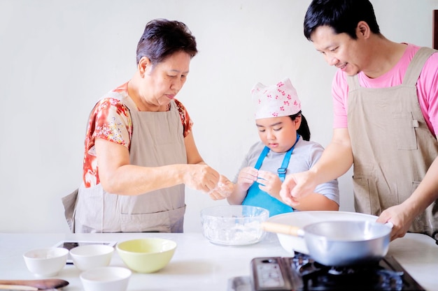 Las familias asiáticas se ayudan mutuamente a cocinar hija padre y abuela en la cocina de su casa