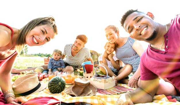 Famílias multirraciais felizes tomando selfie na festa do jardim pic nic