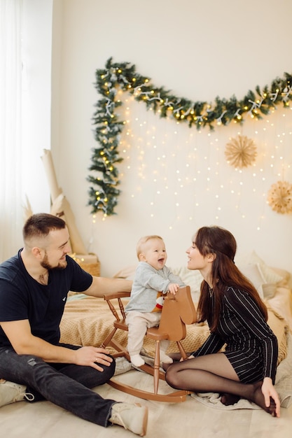 Familias retrato de feliz joven madre y padre con niño posando en el interior del hogar