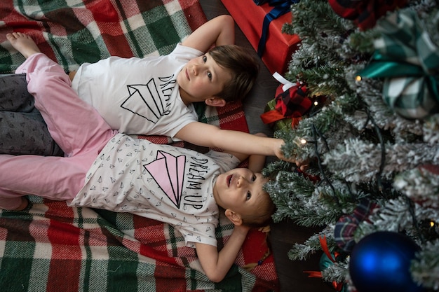 Familie am Heiligabend. Kinder Kinder unter Weihnachtsbaum mit Geschenkboxen. Dekoriertes Wohnzimmer mit traditionellem Kamin. Gemütlicher warmer Winterabend nach Hause.