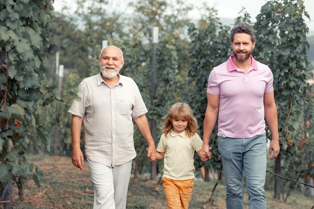 Familie der männlichen Generation zusammen mit drei verschiedenen Generationen im Alter Großvater, Vater und Sohn, die im Frühlingsgarten spazieren gehen