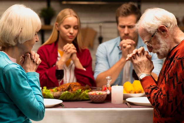 Familie, die an der Vorderansicht des Abendtisches betet