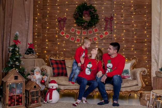 Familie, die auf einer Couch zu Hause nahe dem Weihnachtsbaum sitzt