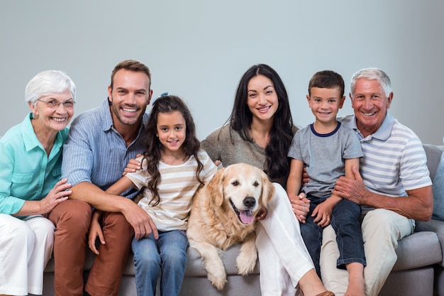 Familie, die auf Sofa mit Hund sitzt