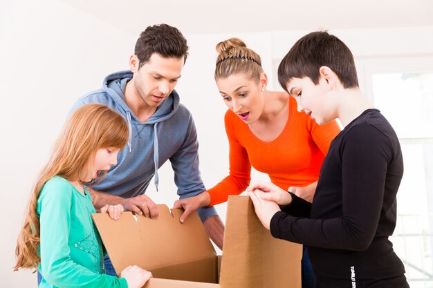 Familie, die bewegliche Kästen im neuen Haus auspackt