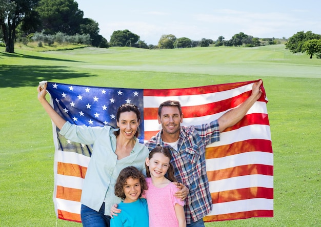 Familie, die eine amerikanische Flagge im Park hält