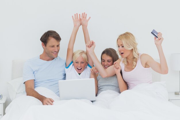 Familie, die einen Laptop im Bett verwendet