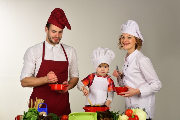 Familie, die glückliche Familie kocht, die zusammen gesundes Essen zu Hause kocht, das im Hausküchengeschirr kocht