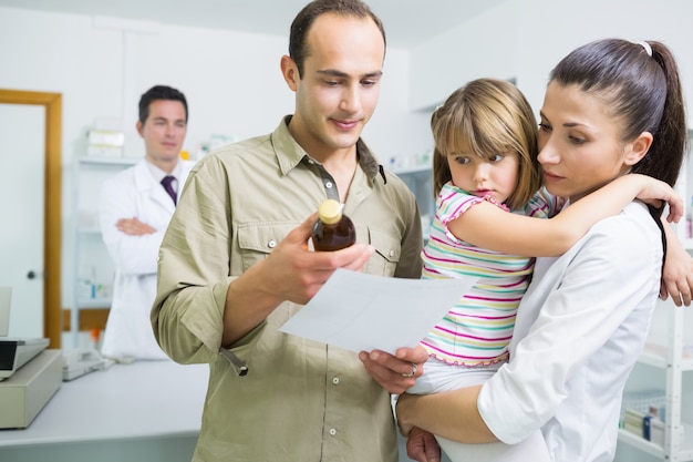 Familie, die Medizin und eine Verordnung in einer Apotheke betrachtet