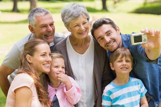 Familie, die mit Digitalkamera im Park sich fotografiert