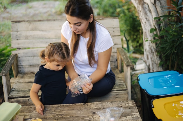 Familie, die Müll zu Hause auf dem Hinterhof-Konzept des Recyclings im Freien für Mutter und Tochter sortiert