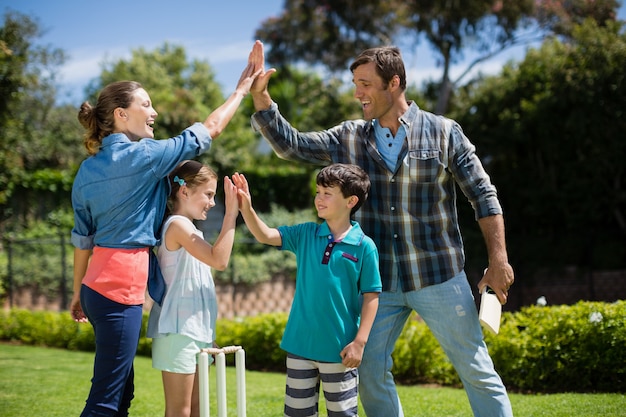 Familie, die sich gegenseitig High Five gibt, während sie Cricket spielt