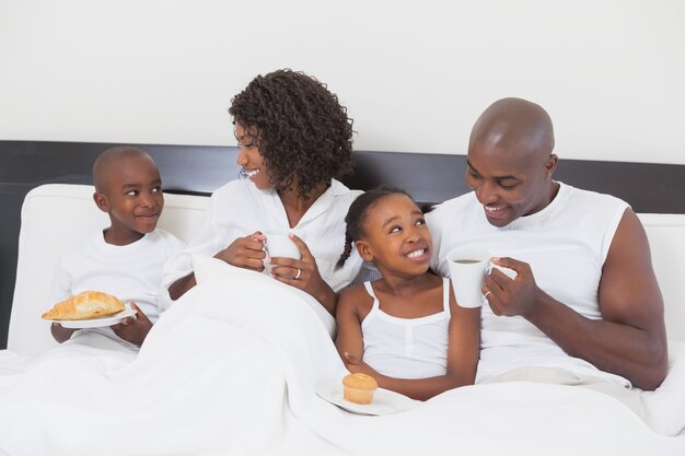 Familie, die sich zusammen im Bett frühstückt entspannt