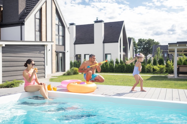 Familie, die Spaß hat. Glückliche Familie, die am Wochenende Spaß beim Chillen in der Nähe des Schwimmbades hat