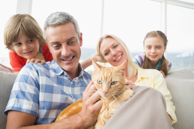 Familie, die zu hause mit katze auf sofa sitzt
