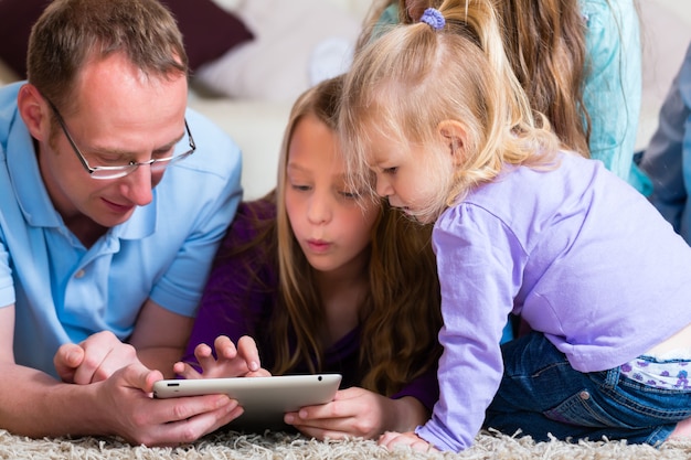 Foto familie, die zu hause mit tablet-computer spielt