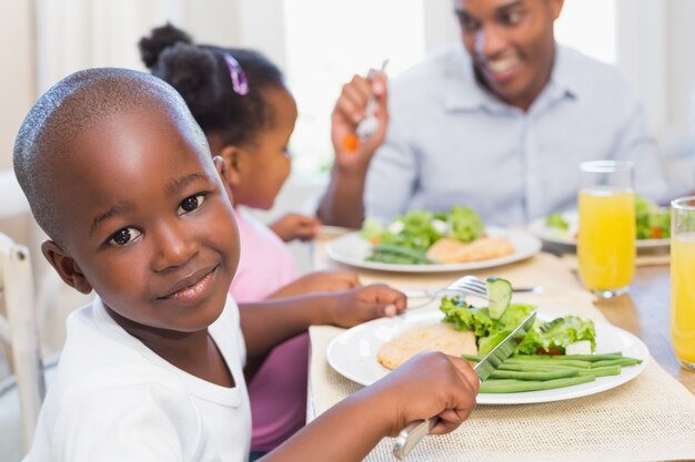 Familie, die zusammen eine gesunde Mahlzeit mit dem Sohn lächelt an der Kamera genießt