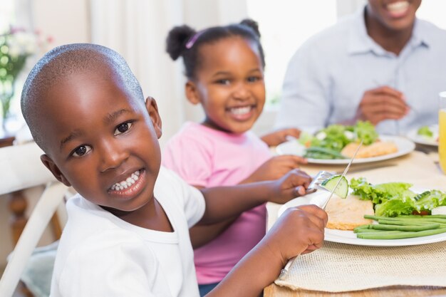 Familie, die zusammen eine gesunde Mahlzeit mit dem Sohn lächelt an der Kamera genießt