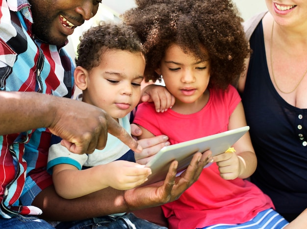 Familie, die zusammen eine Tablette verwendet