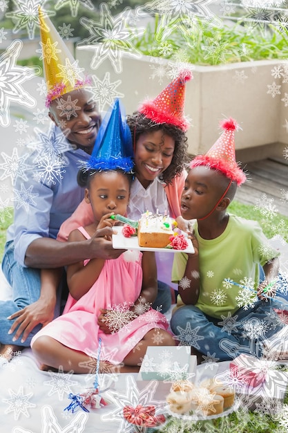 Familie, die zusammen einen Geburtstag im Garten gegen Schneeflocken auf Silber feiert