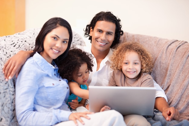 Familie, die zusammen Laptop auf dem Sofa verwendet