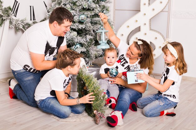 Familie, die zusammen Weihnachtsgeschenke zu Hause öffnet.