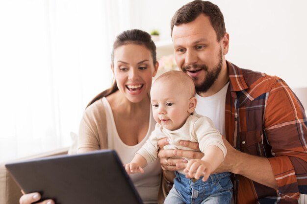 Foto familie elternschaft und menschen konzept glückliche mutter und vater zeigen tablet-pc-computer zum baby zu hause