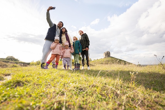 Familie erkundet die Natur und macht Selfie am Telefon Kinder mit Eltern wandern gegen großen Stein im Hügel Pidkamin Ukraine