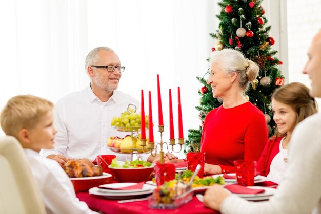 familie, feiertage, generation, weihnachten und personenkonzept - lächelnde familie, die zu hause zu abend isst