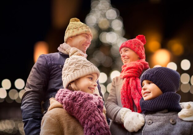 Familie, Feiertage und Menschen Konzept - glückliche Eltern mit Kindern im Freien über Weihnachtsbaum Lichter Hintergrund