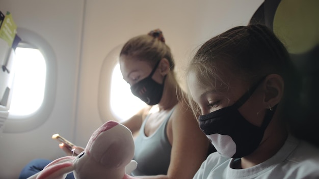 Familie Frau und Kind Baby reisen Tourist Kaukasier im Flugzeug Flugzeug mit medizinischer Schutzmaske Verwenden Sie Smartphone mobile Gesundheitsvirus schützen Coronavirus-Epidemie sarscov2 covid19