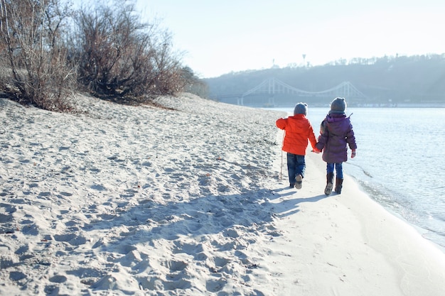 Familie genießt den Winter zusammen, Kinder gehen im Winter am Strand spazieren