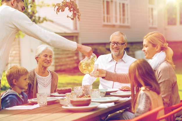 familie, glück, generation, zuhause und personenkonzept - glückliche familie, die feiertagsabendessen im freien hat