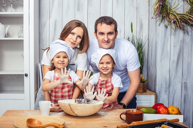 Familie glückliche Mama, Papa und zwei Mädchen Zwillingsschwestern in der Küche backen Kekse aus Mehl.