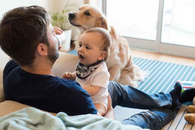 Familie hat Spaß mit einer Babyflasche - Vater, Baby und Hund!