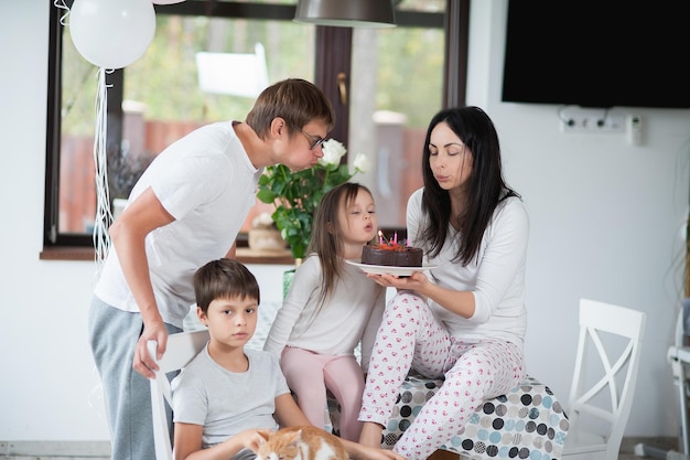 Foto familie im schlafanzug gratuliert mutter zu ihrem geburtstag und gibt ihr einen kuchen