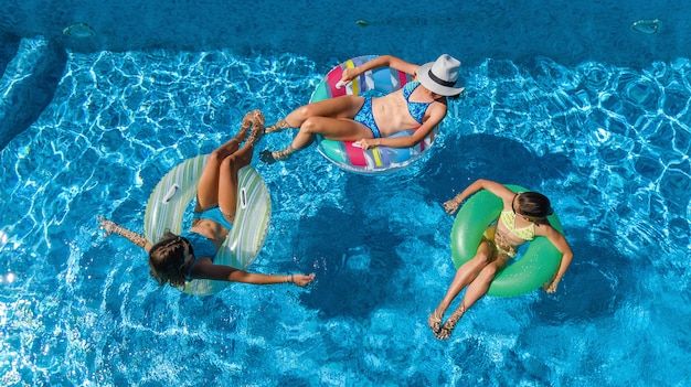 Familie im Schwimmbad Luftdrohnenansicht von oben, glückliche Mutter und Kinder schwimmen auf aufblasbaren Ringkrapfen und haben Spaß im Wasser im Familienurlaub, tropische Ferien im Resort