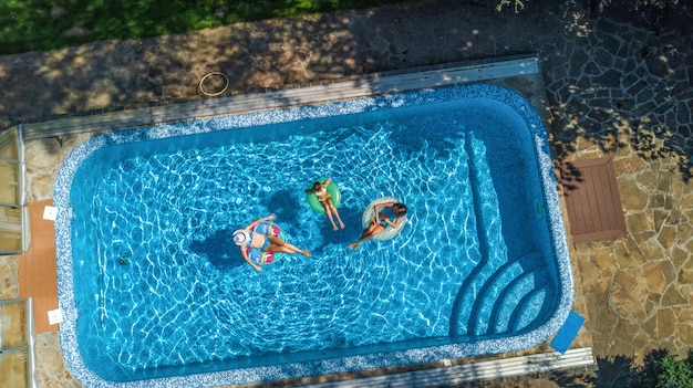 Familie im Schwimmbad Luftdrohnenansicht von oben, glückliche Mutter und Kinder schwimmen auf aufblasbaren Ringkrapfen und haben Spaß im Wasser im Familienurlaub, tropische Ferien im Resort