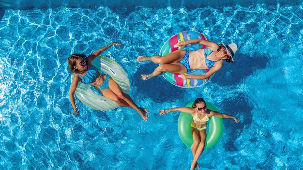 Familie im Schwimmbad Luftdrohnenansicht von oben, glückliche Mutter und Kinder schwimmen auf aufblasbaren Ringkrapfen und haben Spaß im Wasser im Familienurlaub, tropische Ferien im Resort