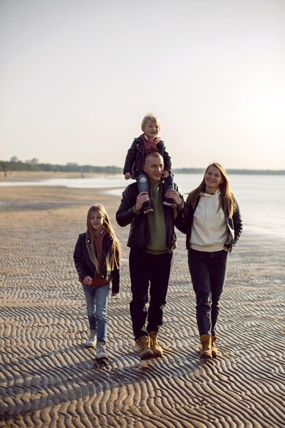 Foto familie in einer lederjacke geht im herbst mit ihrem hund am strand spazieren