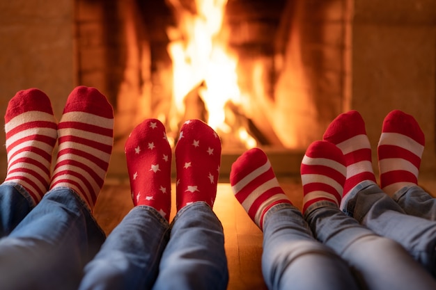 Familie in Weihnachtssocken in der Nähe des Kamins Muttervater und Kinder, die zusammen Spaß haben