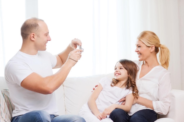 Familie, Kind, Fotografie und Wohnkonzept - lächelnder glücklicher Vater, der Mutter und Tochter fotografiert