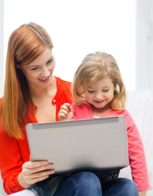 familie, kinder, elternschaft, technologie und internetkonzept - glückliche mutter und tochter mit laptop zu hause