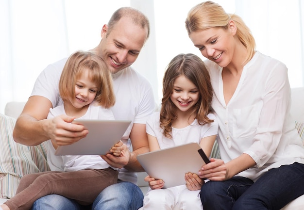 Familie, Kinder, Technologie, Geld und Heimkonzept - lächelnde Familie und zwei kleine Mädchen mit Tablet-PC-Computern zu Hause