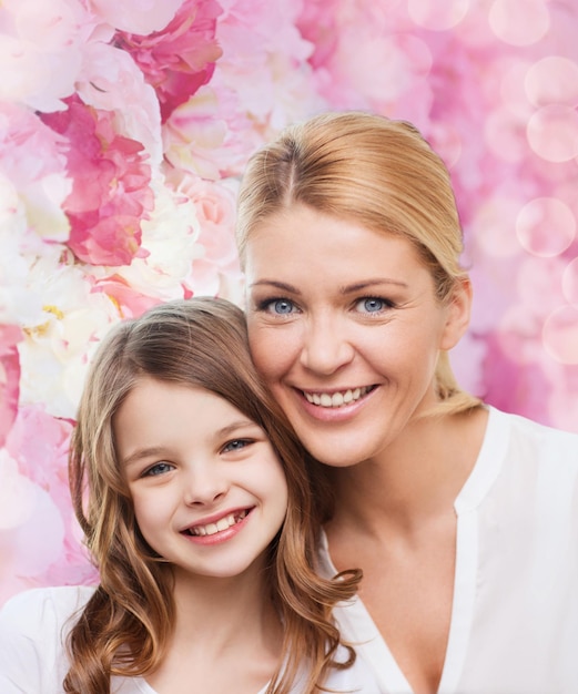 Familie, Kindheit, Glück und Menschen - lächelnde Mutter und kleines Mädchen über rosa Lichthintergrund