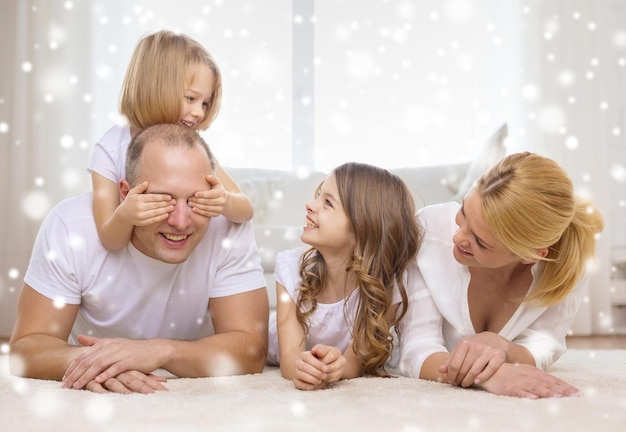 Familie, Kindheit, Menschen und Wohnkonzept - lächelnde Eltern mit zwei kleinen Mädchen, die sich zu Hause amüsieren