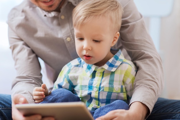 familie, kindheit, vaterschaft, technologie und menschenkonzept - glücklicher vater und sohn mit tablet-pc-computer, der zu hause spielt