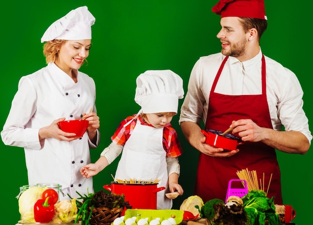 Familie kocht zusammen zu Hause süßes Kind und Eltern in Kochmütze in der Küche gesunder Lebensstil