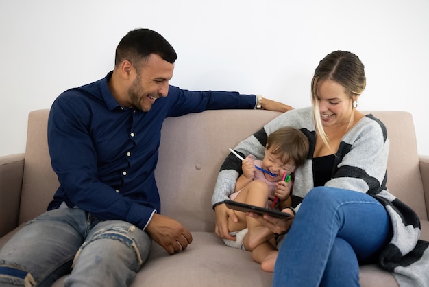 Familie lacht und hat Spaß auf dem Sofa mit dem Tablet